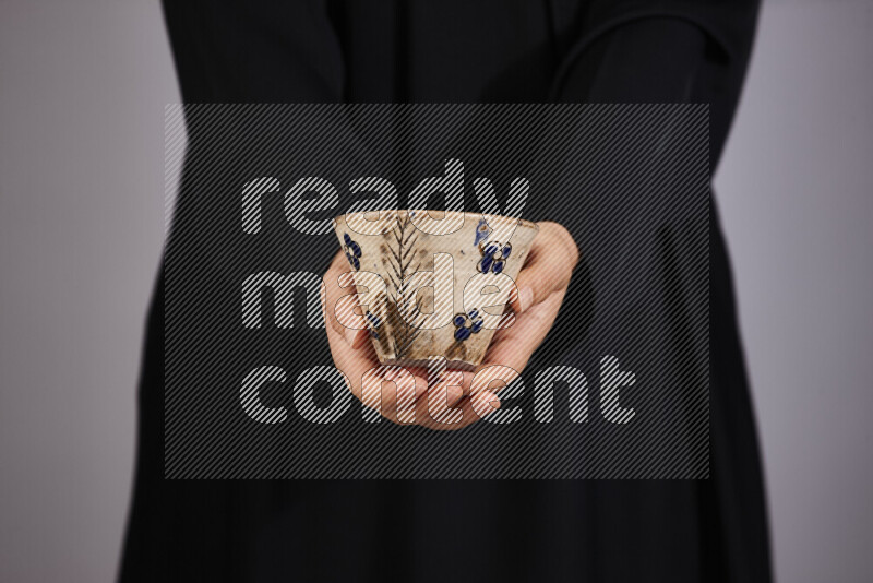 A woman in black abaya holding different pottery essentials in different positions