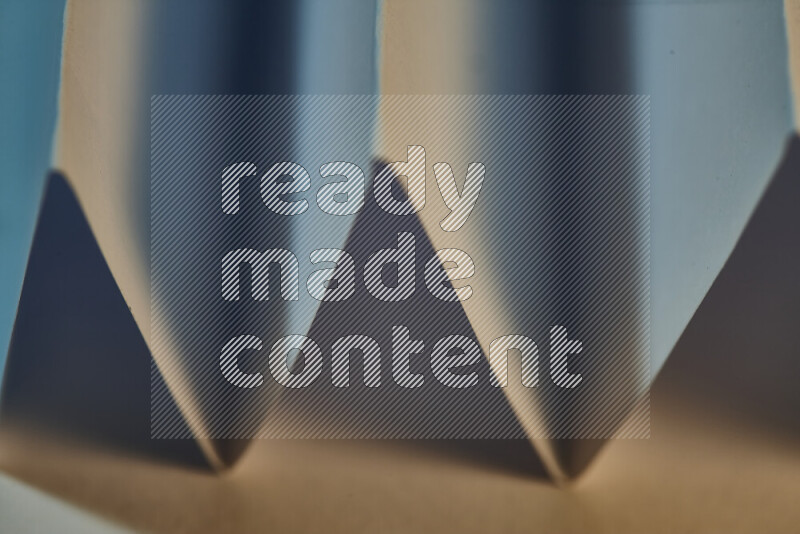 صورة مجردة مقربة تظهر طيات ورقية هندسية حادة بتدرجات اللون الأزرق مع درجات لونية دافئة