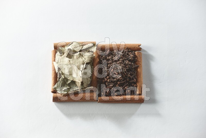 2 squares of cinnamon sticks full of cloves and bay laurel leaves on white flooring