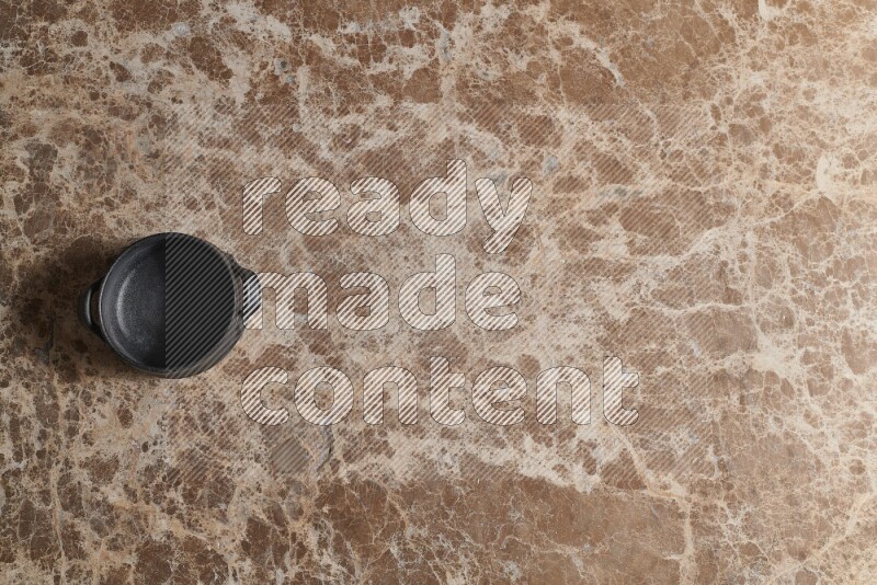 A black pottery bowl on beige marble background