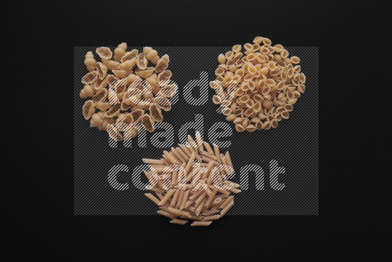 Different pasta types in bunches on black background