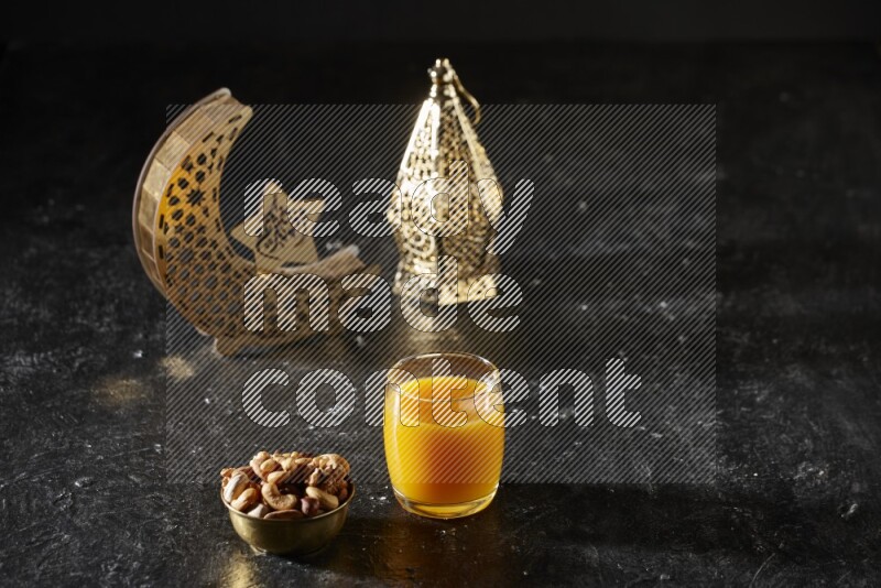 Nuts in a metal bowl with qamar el din beside golden lanterns in a dark setup