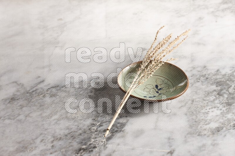 Wheat stalks on decorative pottery plate on grey marble background