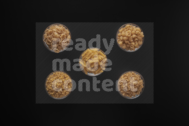 أنواع مختلفة من المعكرونة في أوعية زجاجية علي خلفية سوداء