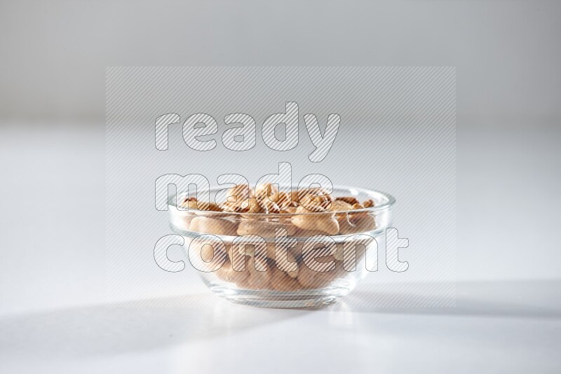 A glass bowl full of cashews on a white background in different angles