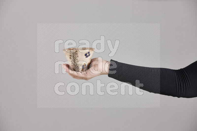 A woman in black abaya holding different pottery essentials in different positions