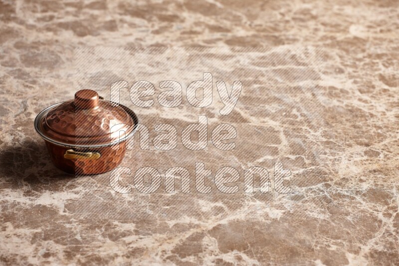 A small copper pot on beige marble background