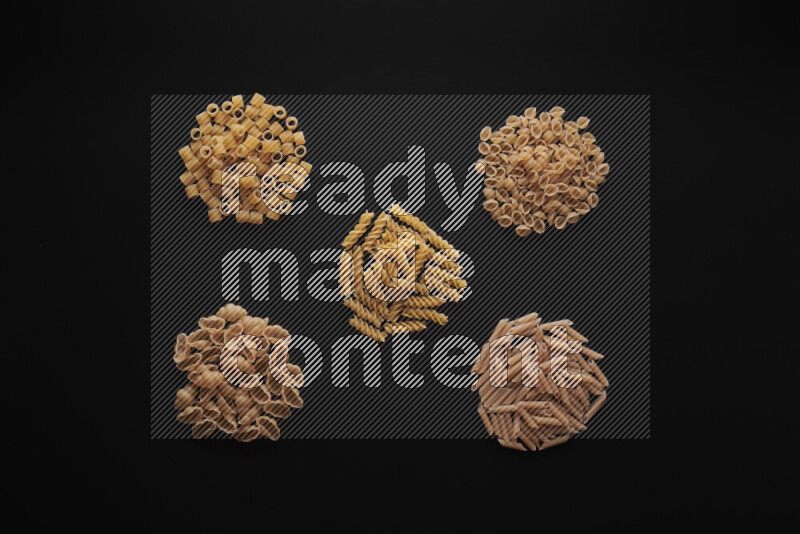 Different pasta types in bunches on black background