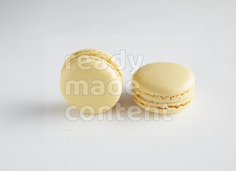 45º Shot of two Yellow Vanilla macarons on white background