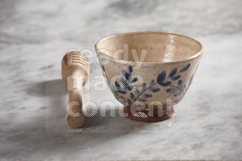 Decorative pottery bowl with wooden honey dipper on the side on grey marble background