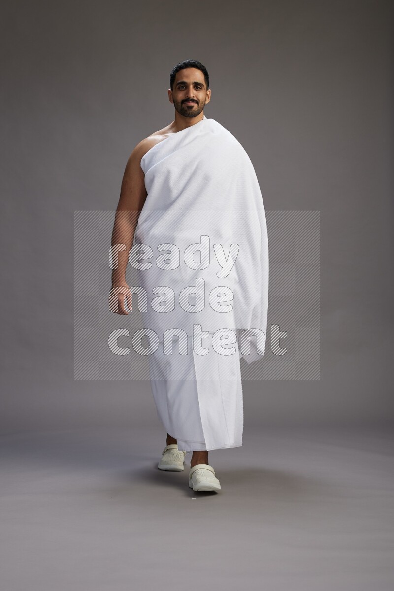 A man wearing Ehram Standing Interacting with the camera on gray background