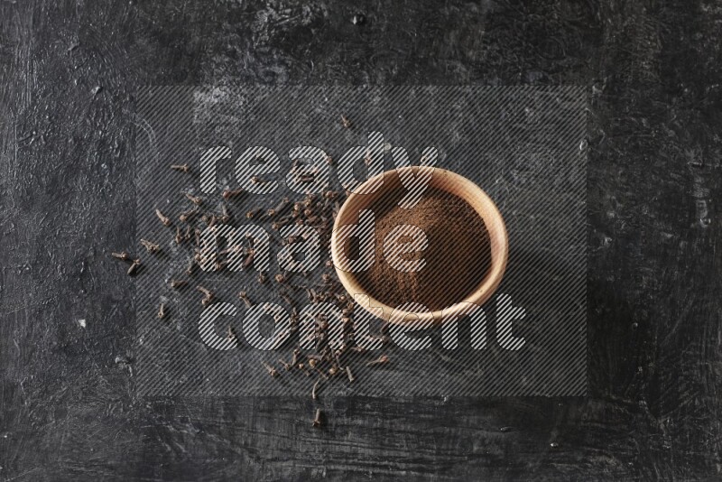 وعاء خشبي ممتلئ ببودرة القرنفل علي خلفية سوداء