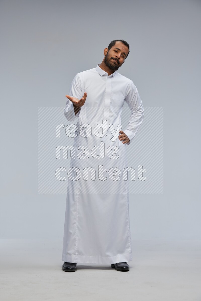 Saudi man Wearing Thob standing interacting with the camera on Gray background