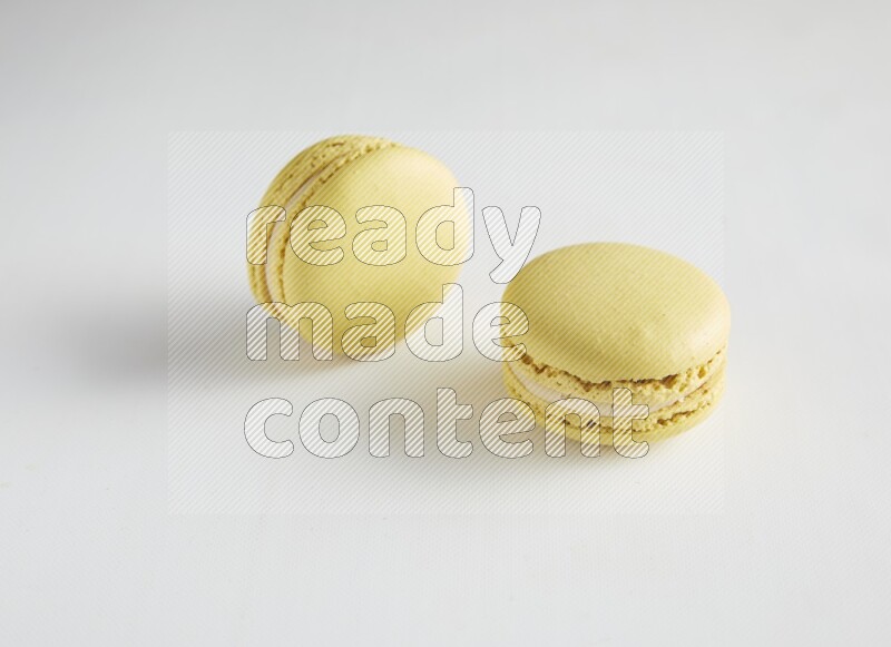 45º Shot of two Yellow Lime macarons on white background