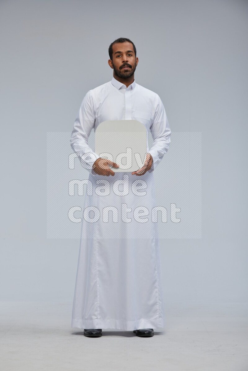 Saudi man wearing Thob standing holding social media sign on Gray background