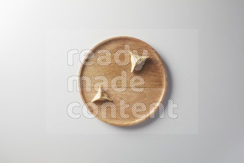 Two Sambosas on a wooden round plate on a white background
