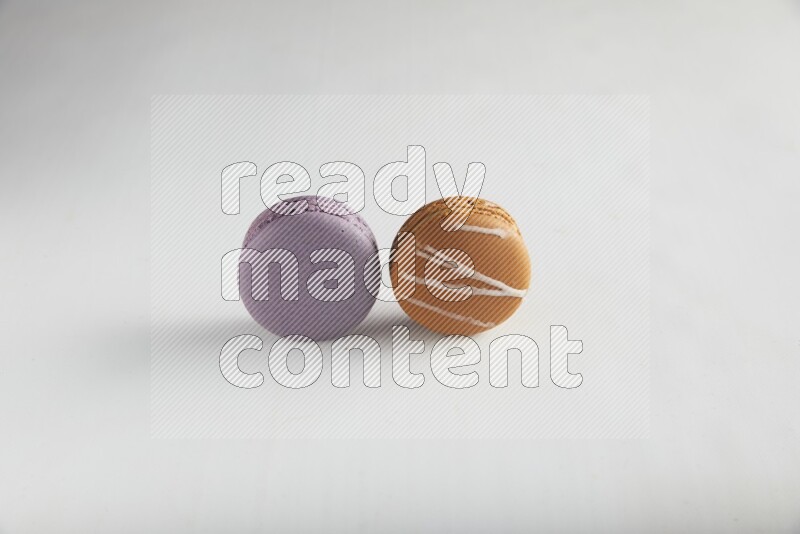 45º Shot of of two assorted Brown Irish Cream, and Purple Blueberry macarons on white background