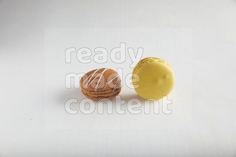 45º Shot of of two assorted Brown Irish Cream, and Yellow Lemon macarons on white background
