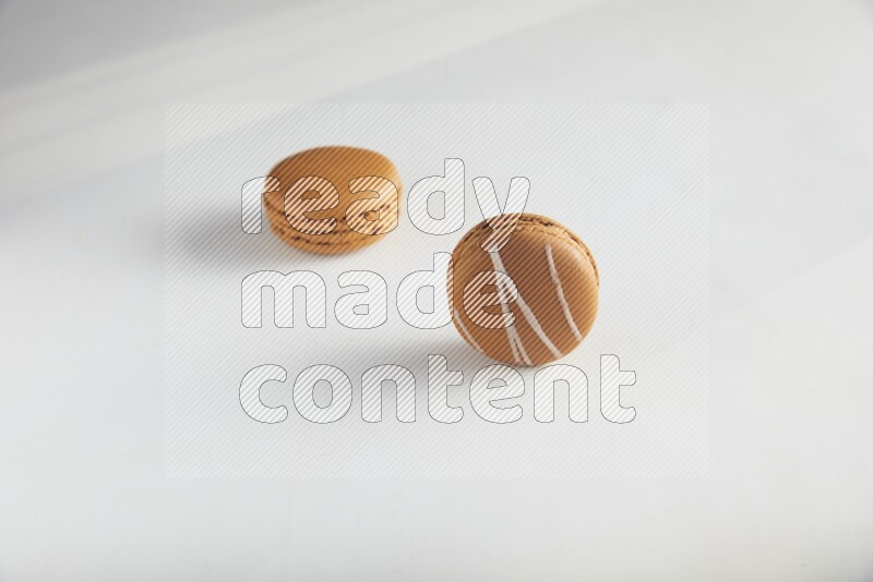 45º Shot of of two assorted Brown Irish Cream, and Brown Maple Taffy macarons  on white background
