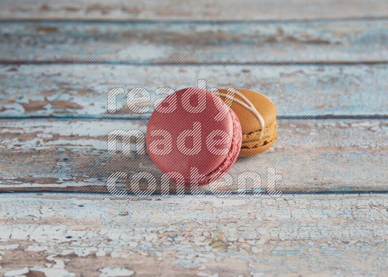45º Shot of of two assorted Brown Irish Cream, and Pink Raspberry macarons on light blue background