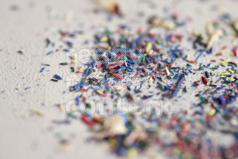 This image showcases a vibrant multicolored pencil shavings scattered on grey background