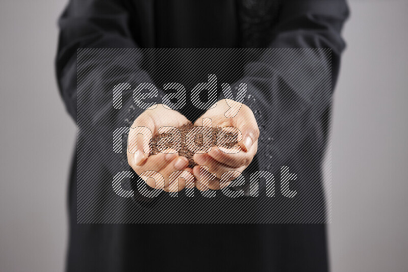 Woman in abaya holding different kinds of spices in different positions