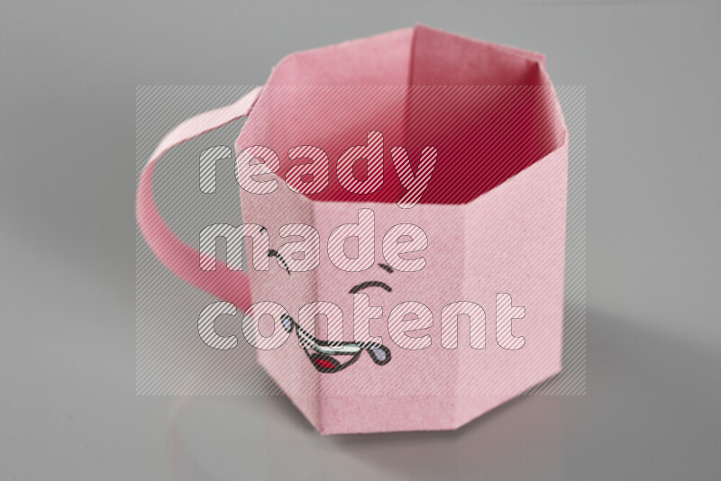 Origami cup on grey background