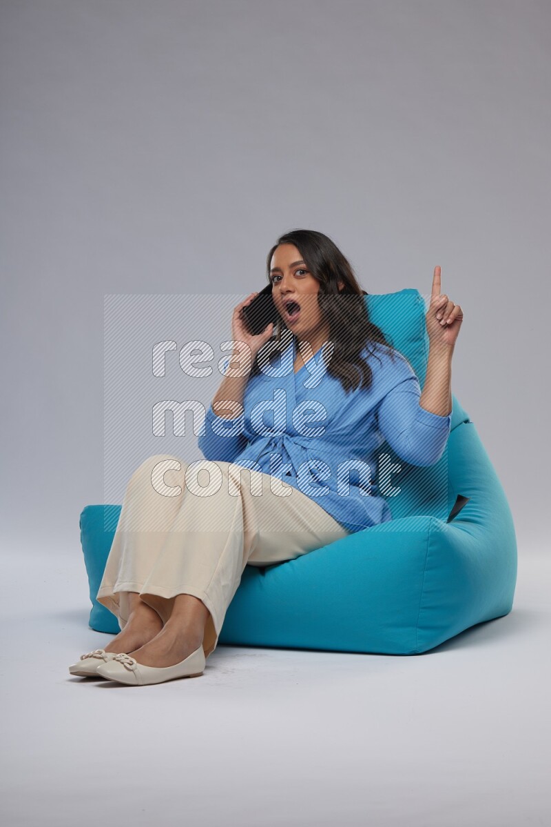 A woman sitting on a blue beanbag and talking on the phone