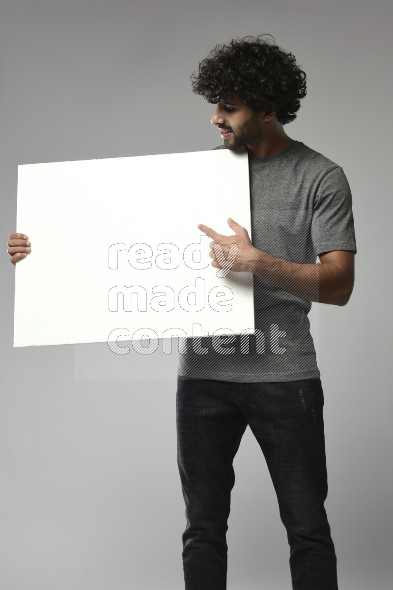 A man wearing casual standing and holding a white board on white background