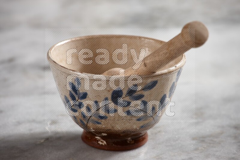 Decorative pottery bowl with wooden honey dipper in it on grey marble background