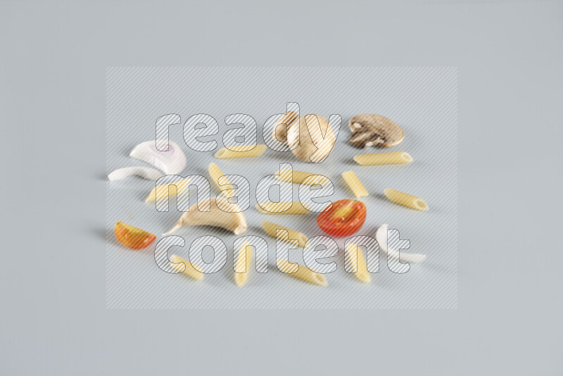 Raw pasta with different ingredients such as cherry tomatoes, garlic, onions, red chilis, black pepper, white pepper, bay laurel leaves, rosemary, cardamom and mushrooms on light blue background