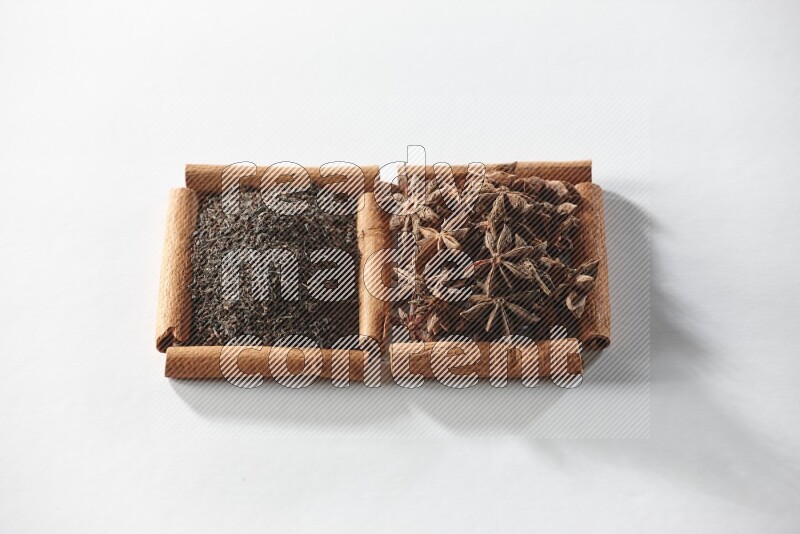 2 squares of cinnamon sticks full of star anise and black tea on white flooring