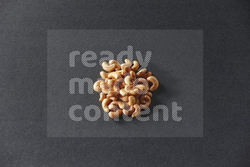 A bunch of cashews on a black background in different angles