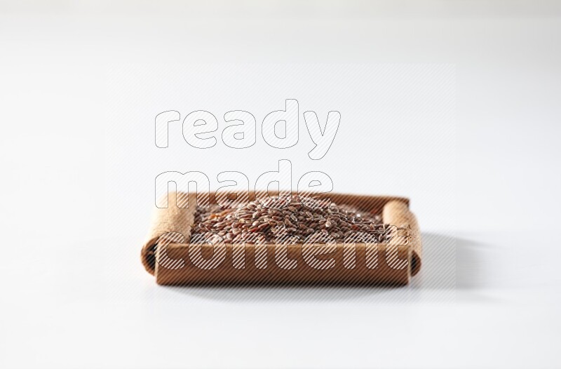 A single square of cinnamon sticks full of flaxseeds on white flooring