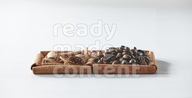 مربعان من أعواد القرفة ممتلئان بحبوب القهوة وقطع من القرفة علي خلفية بيضاء