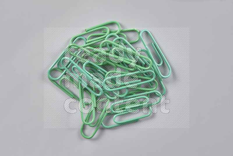 Green paper clips isolated on a grey background