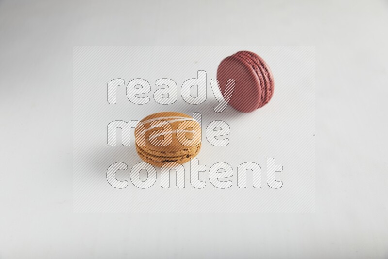 45º Shot of of two assorted Brown Irish Cream, and Red Velvet macarons on white background