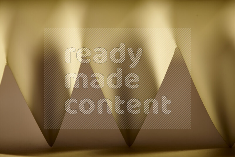 A close-up abstract image showing sharp geometric paper folds in warm gradients