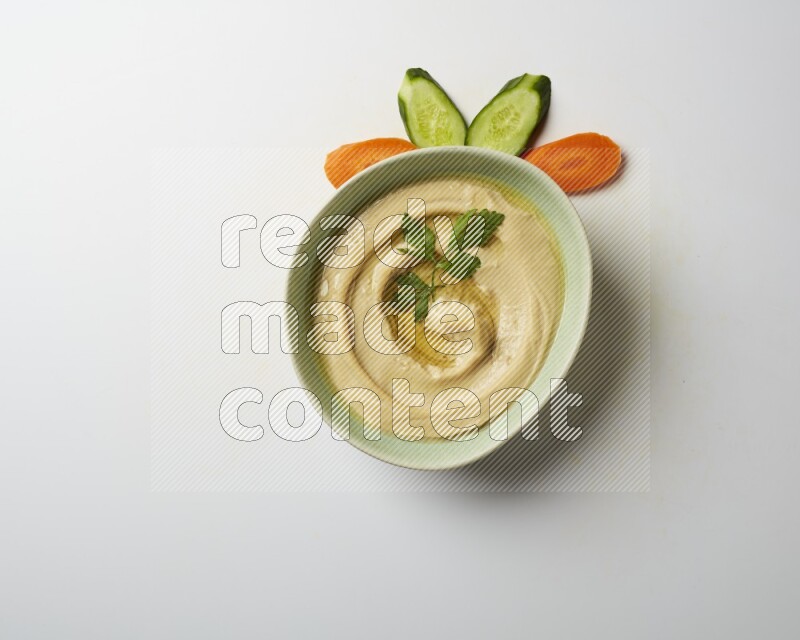 Hummus in a green plate garnished with parsley on a white background