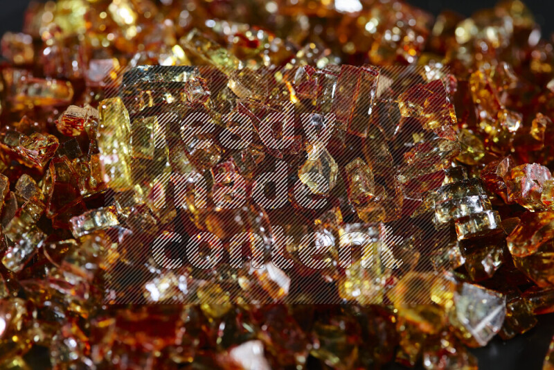 Transparent orange fragments of glass scattered on a black background
