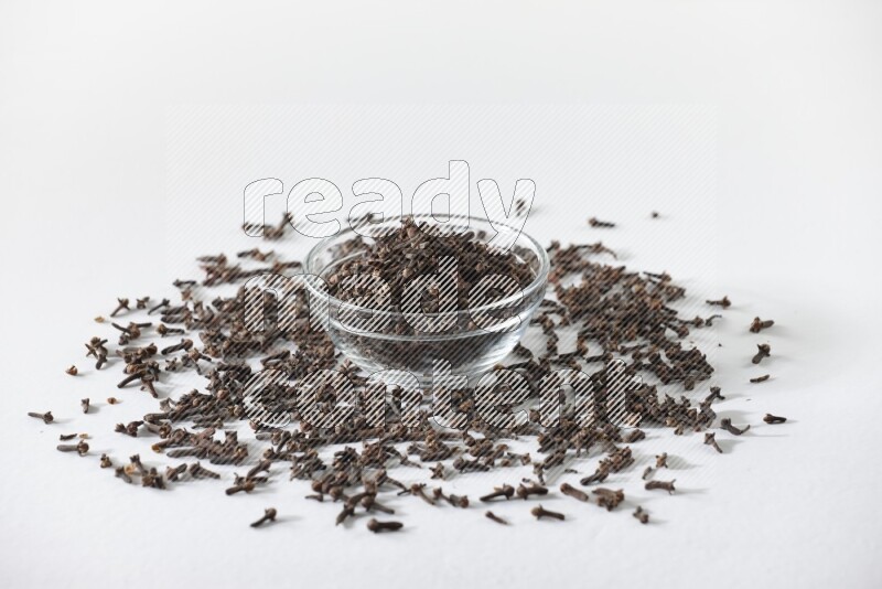 A glass bowl full of cloves on a white flooring