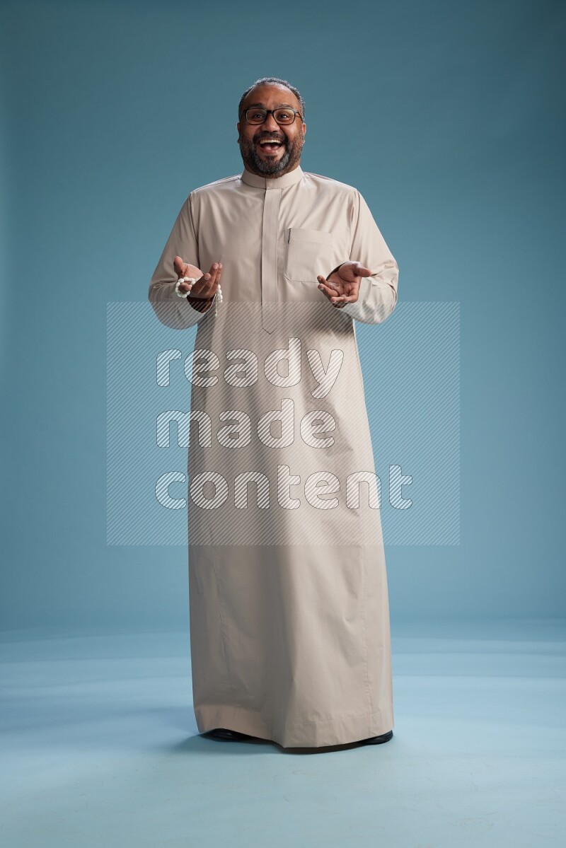 Saudi Man without shimag Standing Interacting with the camera on blue background