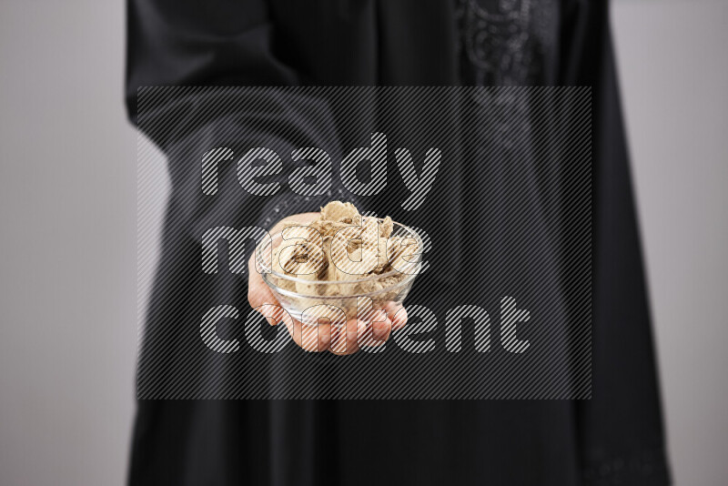 Woman in abaya holding different kinds of spices in different positions