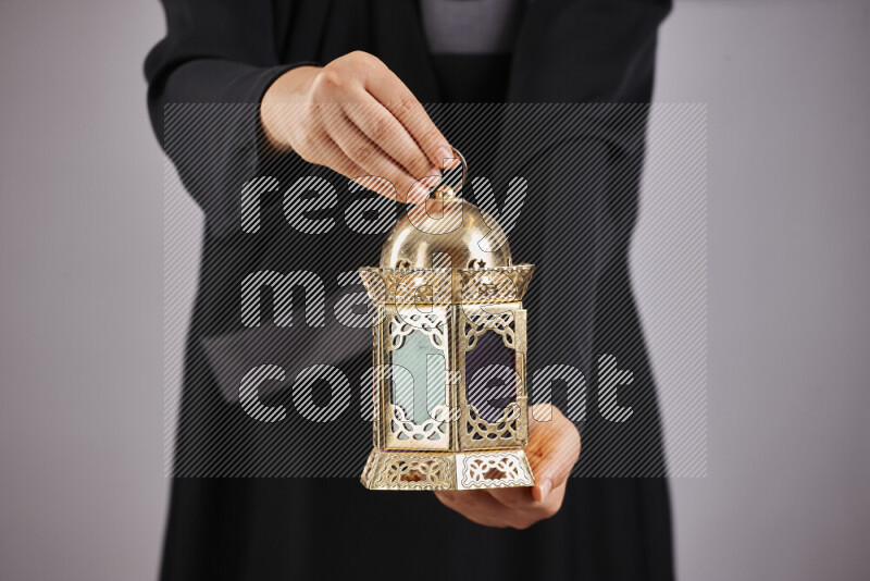 A woman in black abaya holding different ramadan lanterns in different positions