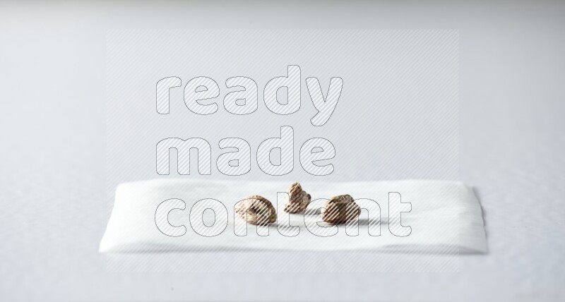 3 peeled pistachios on a piece of paper on a white background in different angles