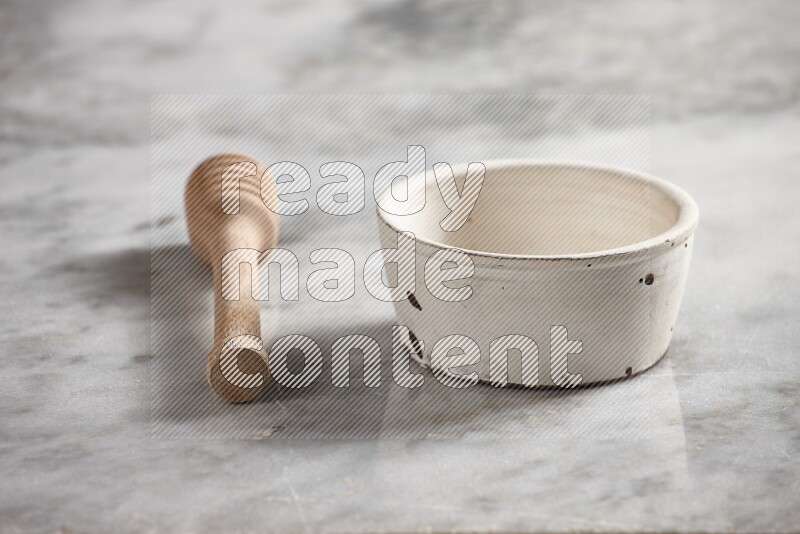 White pottery bowl with wooden honey dipper on the side on grey marble background