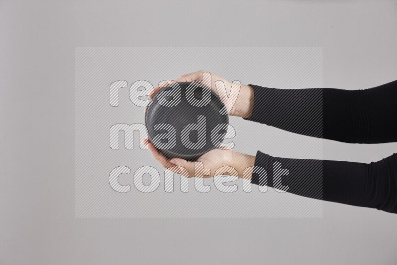 A woman in black abaya holding different pottery essentials in different positions