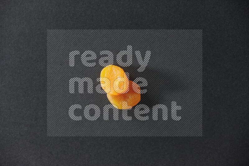 Two dried apricots on a black background in different angles