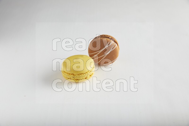 45º Shot of of two assorted Brown Irish Cream, and Yellow Lemon macarons on white background