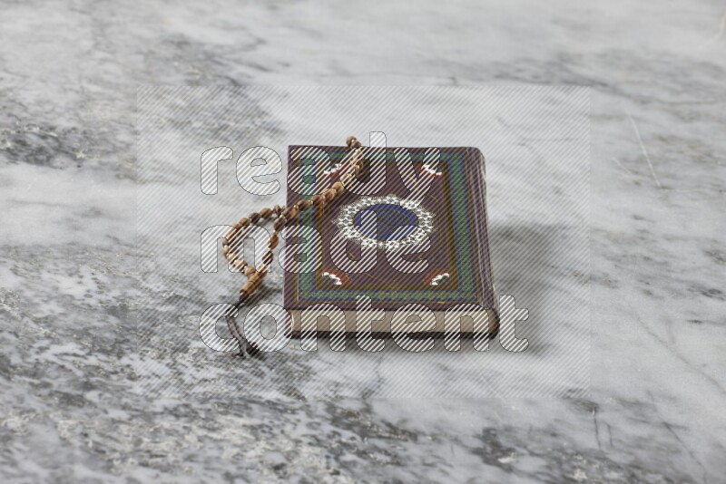 Quran with a prayer beads on grey marble background